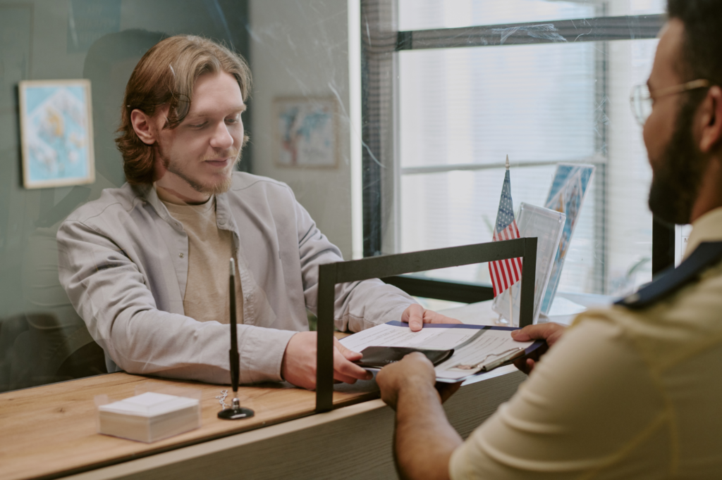 Student submitting passport and documents for European student visa application at embassy counter